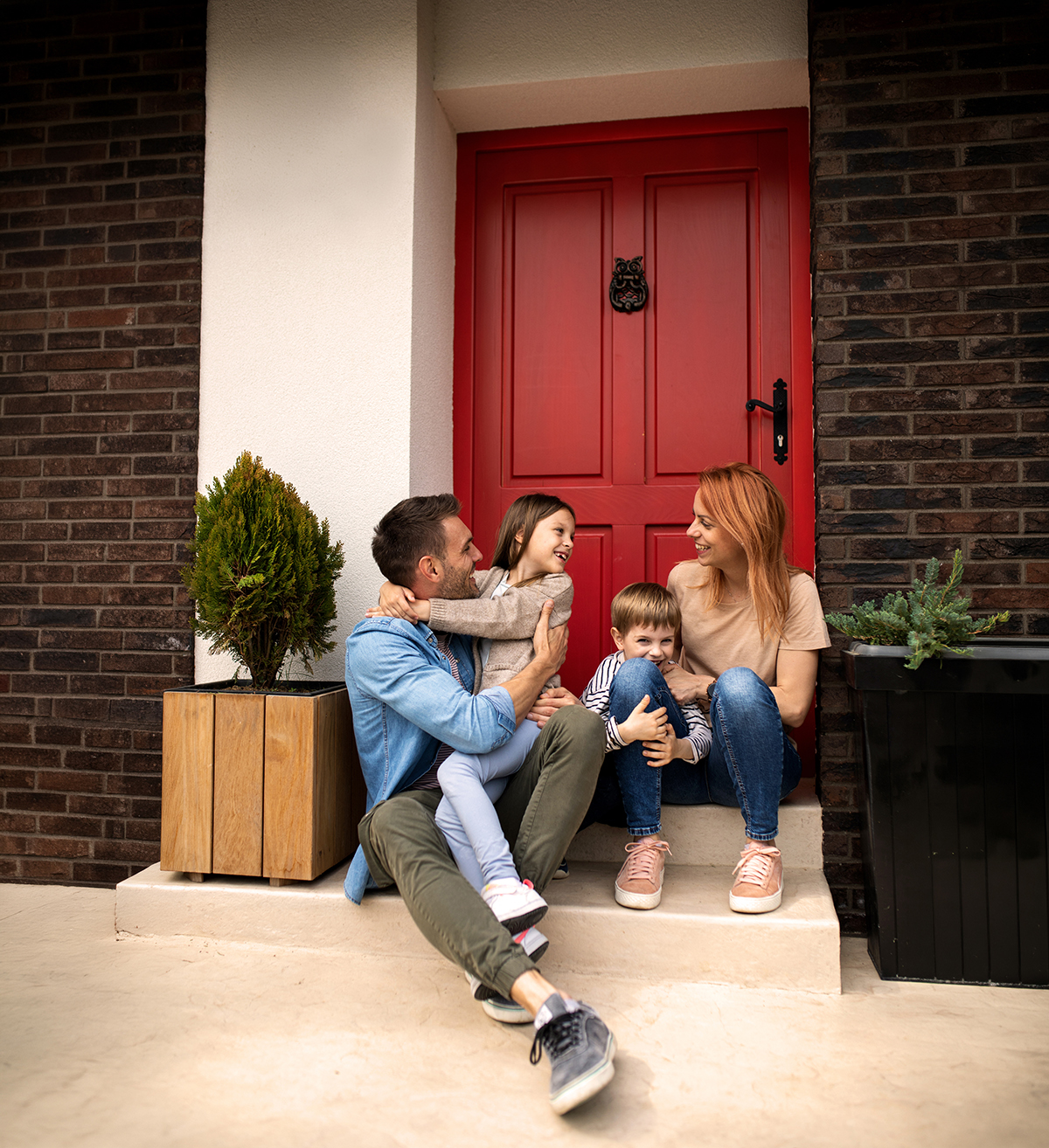 Young parents with children sitting in front of their house porch