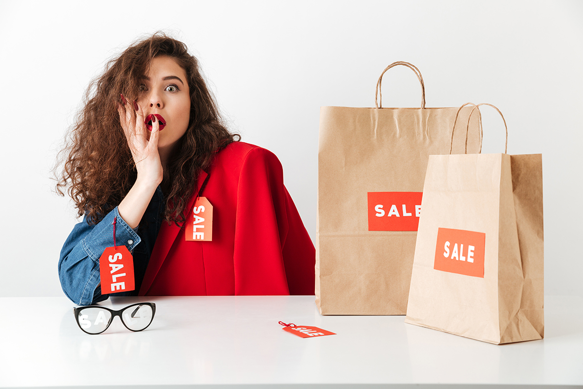 Excited shocked sale woman sitting with paper shopping bags