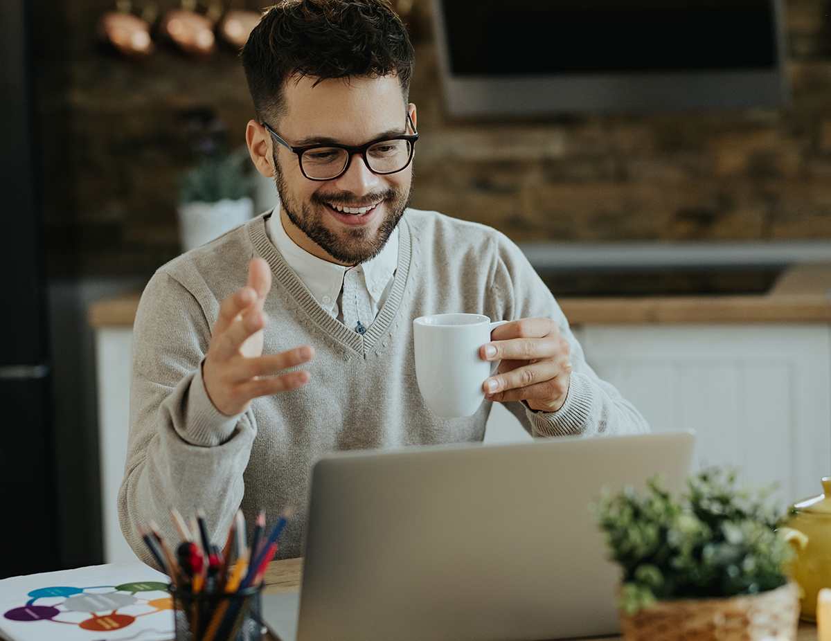 Happy entrepreneur drinking coffee during conference call over l